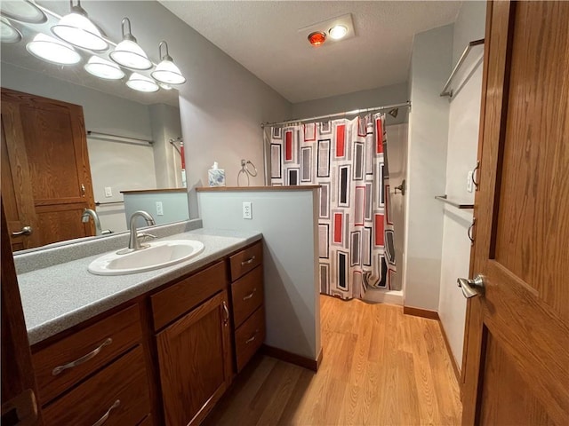 bathroom with hardwood / wood-style flooring, vanity, and walk in shower