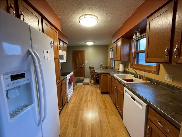 kitchen featuring a textured ceiling, sink, white appliances, and light hardwood / wood-style flooring