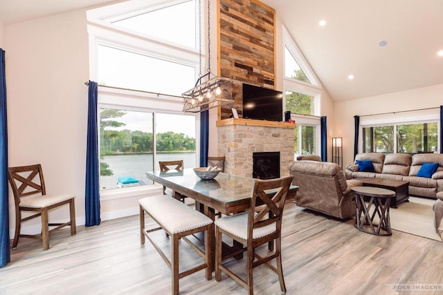 dining room featuring a fireplace, light hardwood / wood-style floors, and high vaulted ceiling