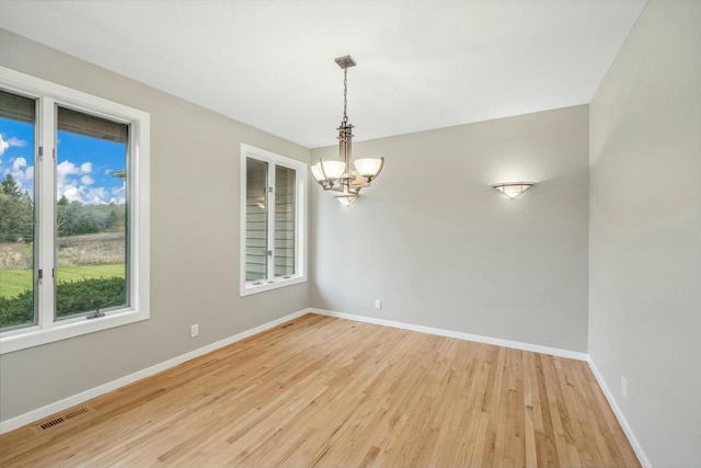 spare room with light wood-type flooring and a notable chandelier