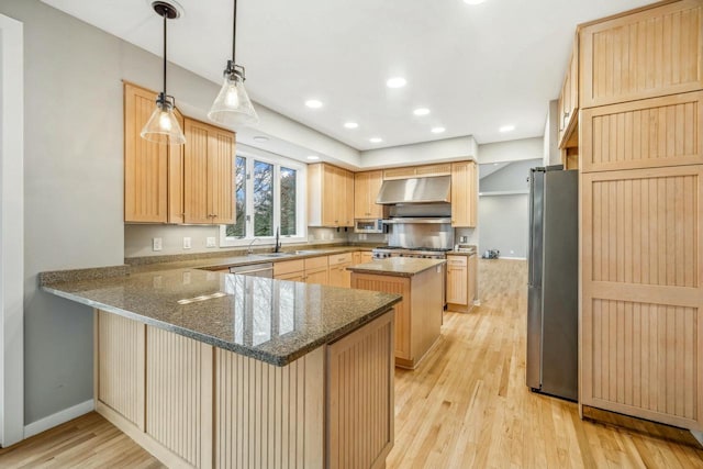 kitchen with kitchen peninsula, appliances with stainless steel finishes, dark stone counters, exhaust hood, and light hardwood / wood-style floors