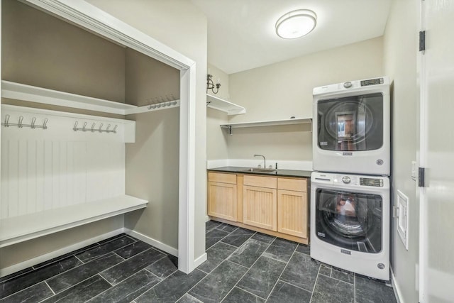 washroom featuring cabinets, sink, and stacked washing maching and dryer