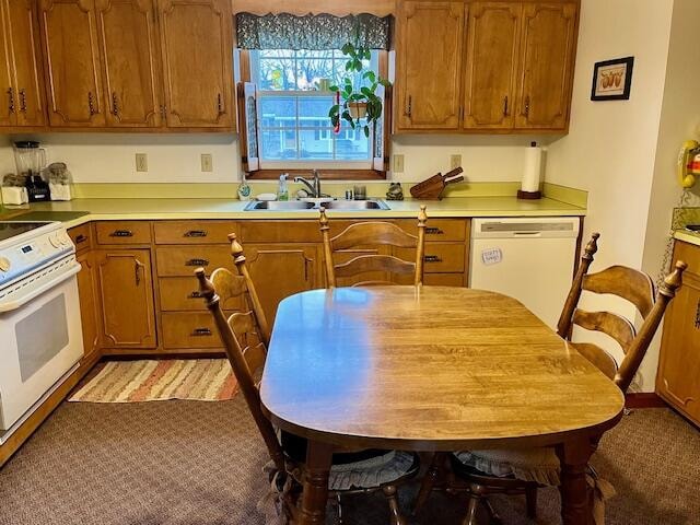 kitchen featuring brown cabinetry, white appliances, light countertops, and a sink