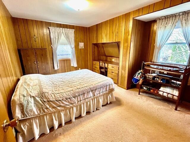 carpeted bedroom featuring wood walls