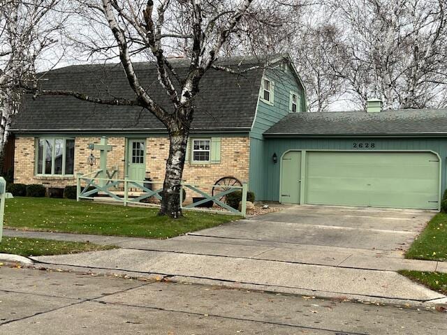 colonial inspired home featuring roof with shingles, concrete driveway, an attached garage, a gambrel roof, and a front yard