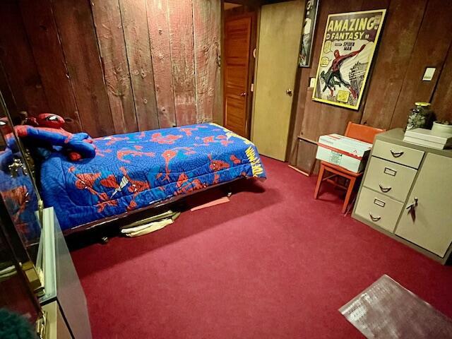 bedroom with carpet floors and wooden walls