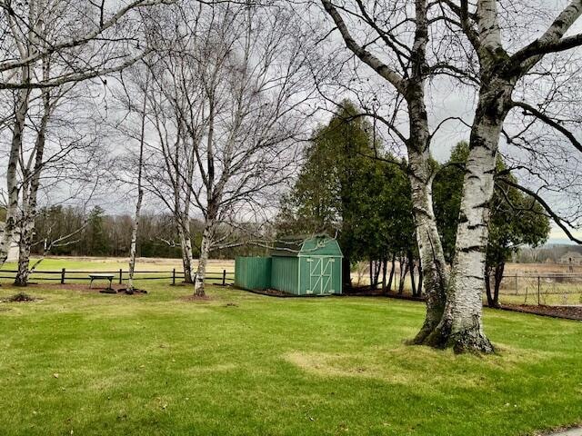 view of yard with fence, an outdoor structure, and a shed