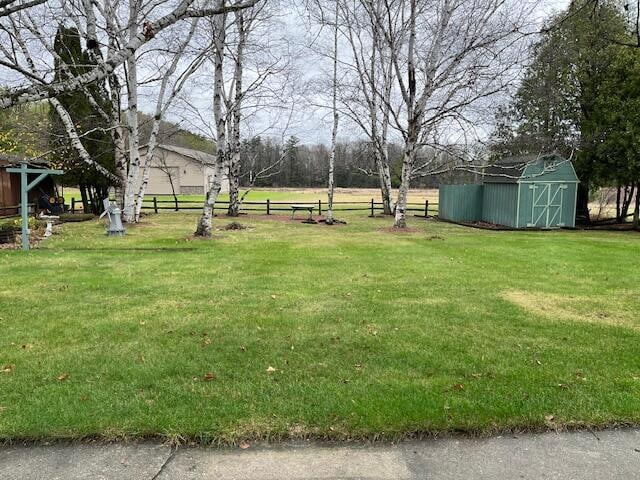 view of yard featuring a shed, fence, and an outdoor structure