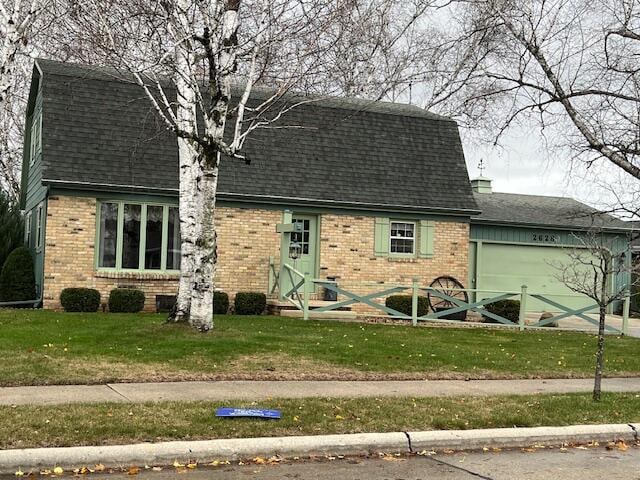 colonial inspired home with brick siding, a chimney, a front lawn, and roof with shingles