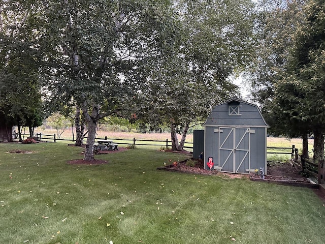 exterior space featuring a rural view, fence, an outdoor structure, and a storage unit