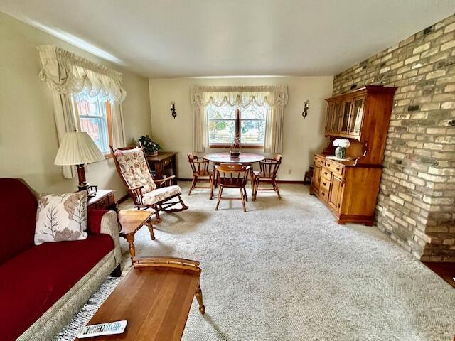 sitting room with baseboards, light colored carpet, and a healthy amount of sunlight