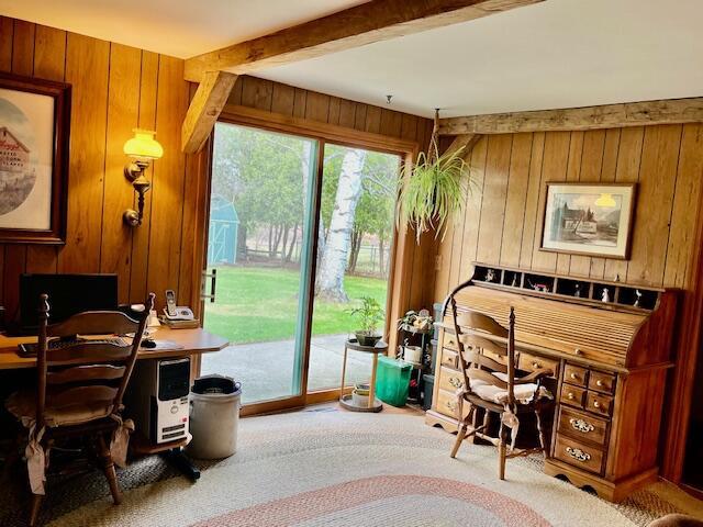 home office featuring carpet, beamed ceiling, and wooden walls