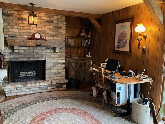 home office featuring wood walls and a brick fireplace