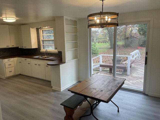 unfurnished dining area featuring a chandelier, sink, and wood-type flooring