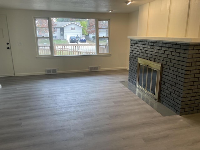 unfurnished living room featuring wood-type flooring, a fireplace, and a wealth of natural light