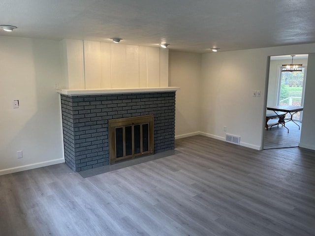 unfurnished living room with wood-type flooring and a brick fireplace