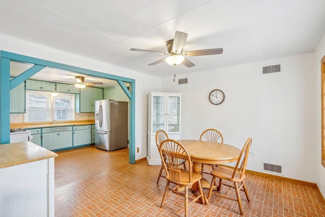 dining area with ceiling fan and sink