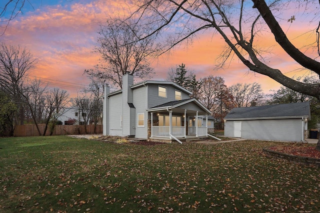 view of front of home featuring covered porch, an outdoor structure, and a yard