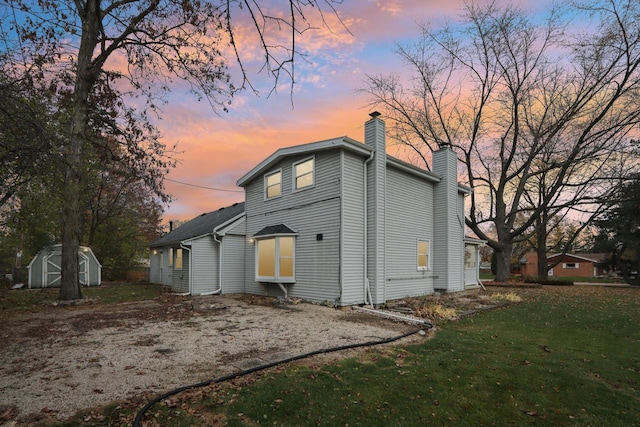 back house at dusk featuring a yard and a shed