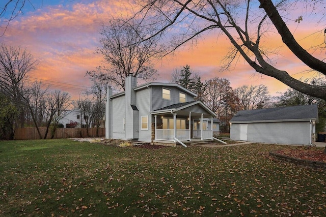 view of front of property featuring covered porch, an outbuilding, and a lawn