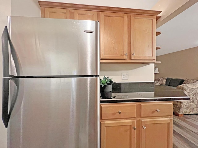 kitchen with tile counters, light brown cabinetry, stainless steel fridge, and light wood-type flooring