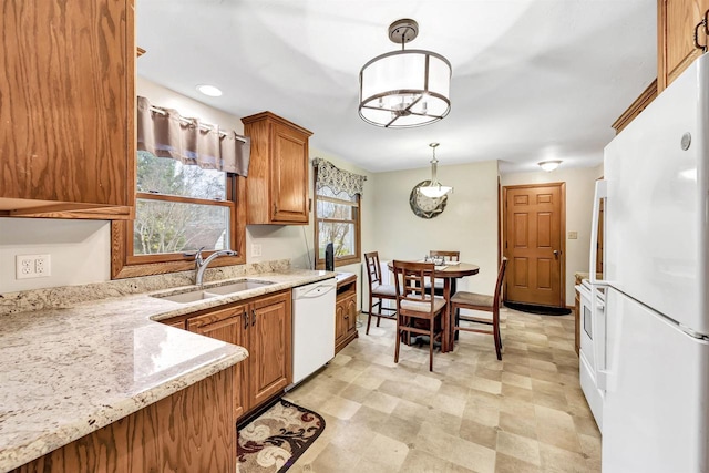 kitchen with light stone countertops, sink, a chandelier, pendant lighting, and white appliances