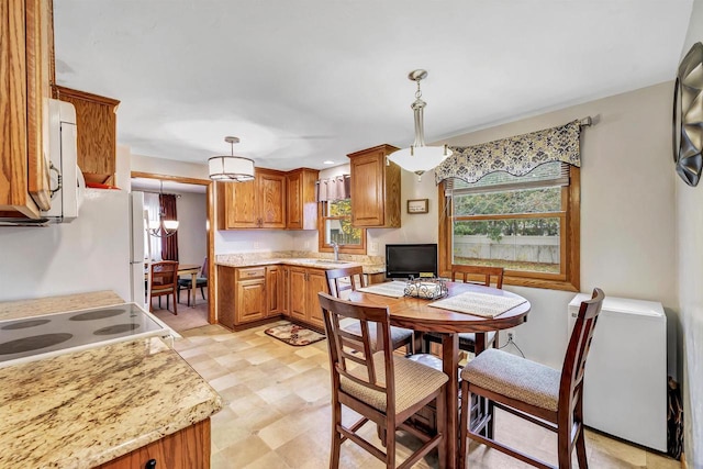 kitchen featuring light stone countertops, sink, a chandelier, range, and hanging light fixtures