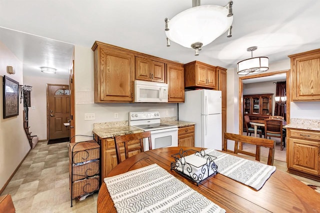 kitchen with decorative light fixtures, light stone counters, and white appliances