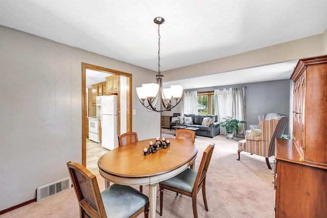 carpeted dining room with a chandelier