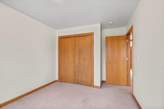 unfurnished bedroom with light colored carpet and a closet