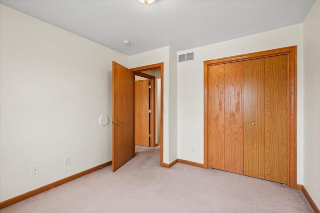 unfurnished bedroom featuring light carpet and a closet