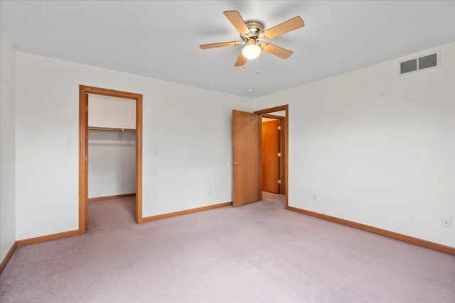 unfurnished bedroom with a walk in closet, ceiling fan, a closet, and light carpet