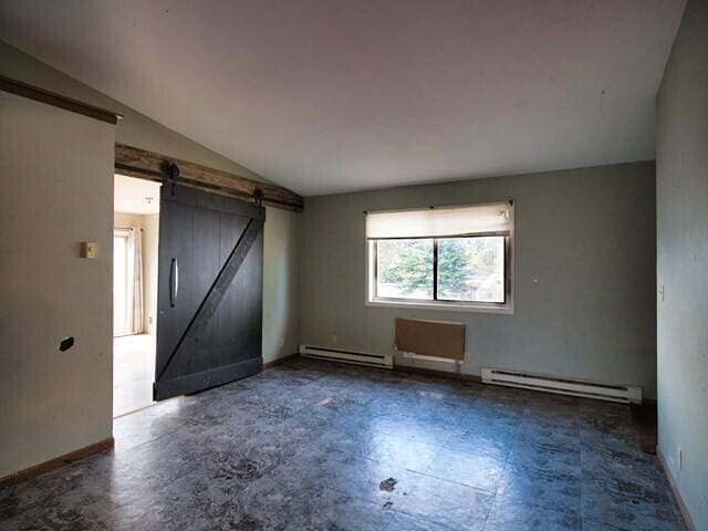 spare room with baseboard heating, a barn door, and vaulted ceiling