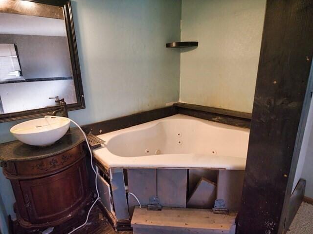 bathroom with vanity and tiled tub