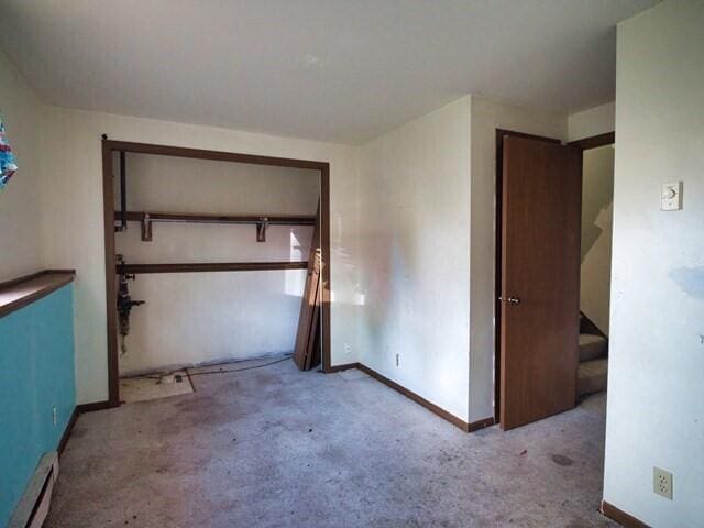 unfurnished bedroom featuring baseboard heating and a closet