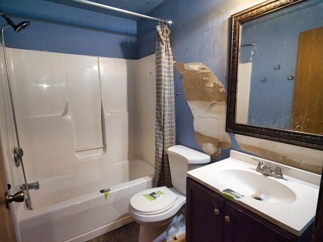 full bathroom with hardwood / wood-style floors, vanity, toilet, and shower / bath combo with shower curtain