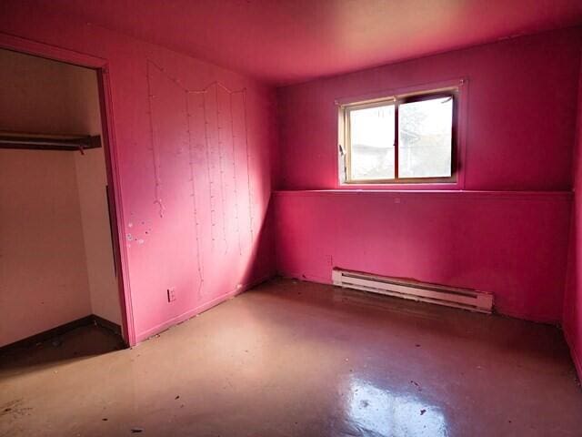 interior space featuring concrete floors, baseboard heating, and a closet