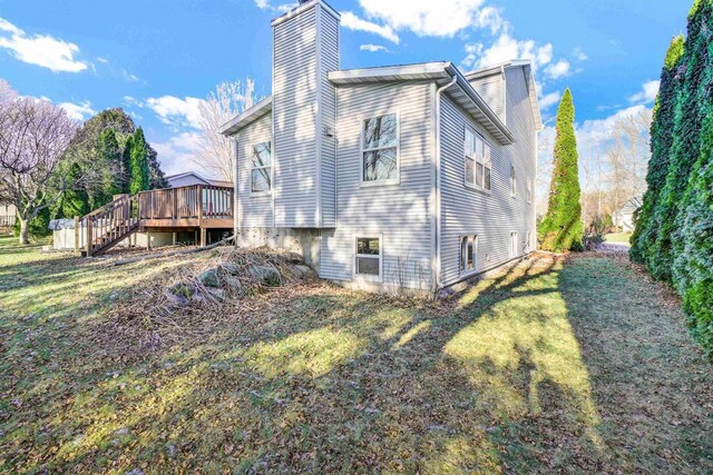 rear view of house featuring a lawn and a deck