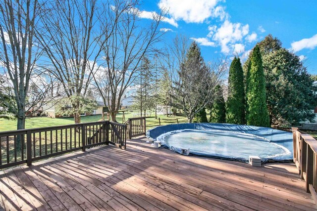 deck featuring a yard and a covered pool