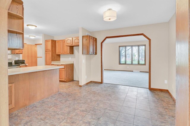 kitchen with kitchen peninsula, stove, and light colored carpet