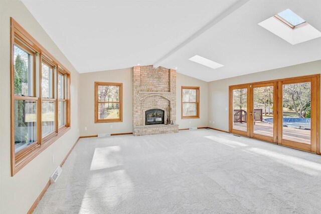 unfurnished living room with a fireplace, light carpet, and vaulted ceiling with skylight