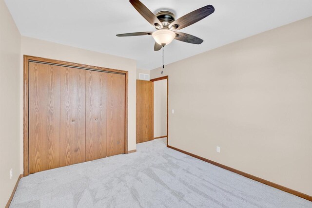 unfurnished bedroom featuring a closet, ceiling fan, and light colored carpet