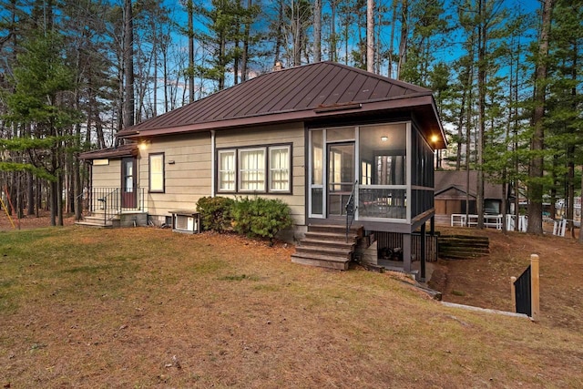 view of front of home with a lawn, central AC, and a sunroom