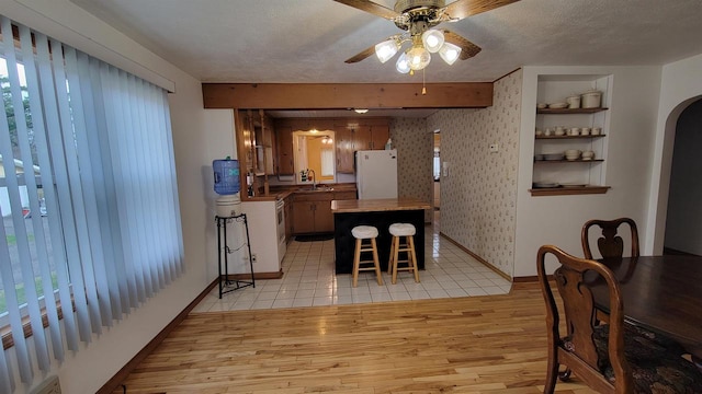 dining area with ceiling fan, light wood-type flooring, a textured ceiling, and a wealth of natural light