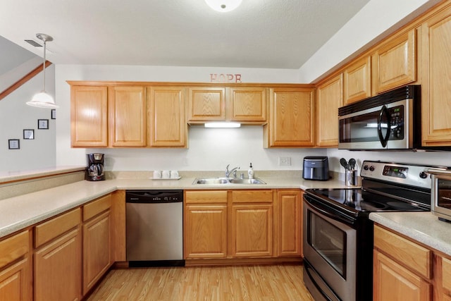 kitchen with sink, hanging light fixtures, light hardwood / wood-style floors, vaulted ceiling, and appliances with stainless steel finishes