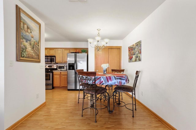 dining area featuring light hardwood / wood-style flooring and a notable chandelier