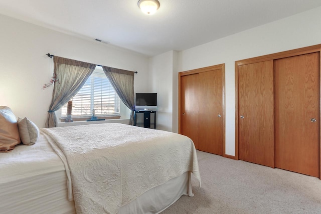 bedroom with light carpet and multiple closets