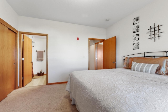 bedroom with light colored carpet, a closet, and ensuite bathroom