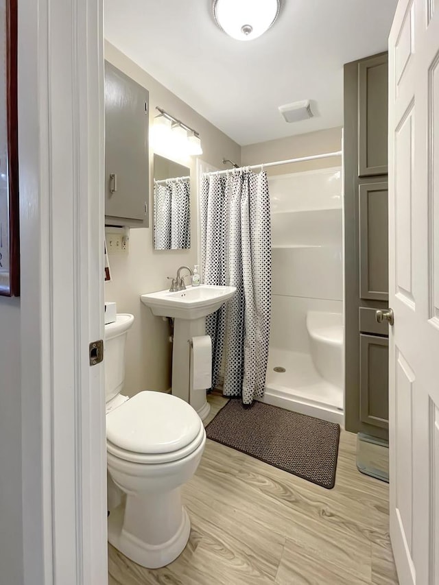 bathroom with curtained shower, hardwood / wood-style floors, and toilet