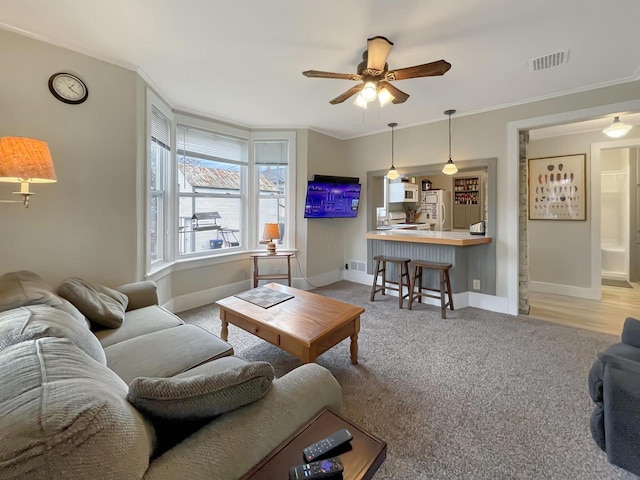 living room with ceiling fan, light wood-type flooring, and crown molding